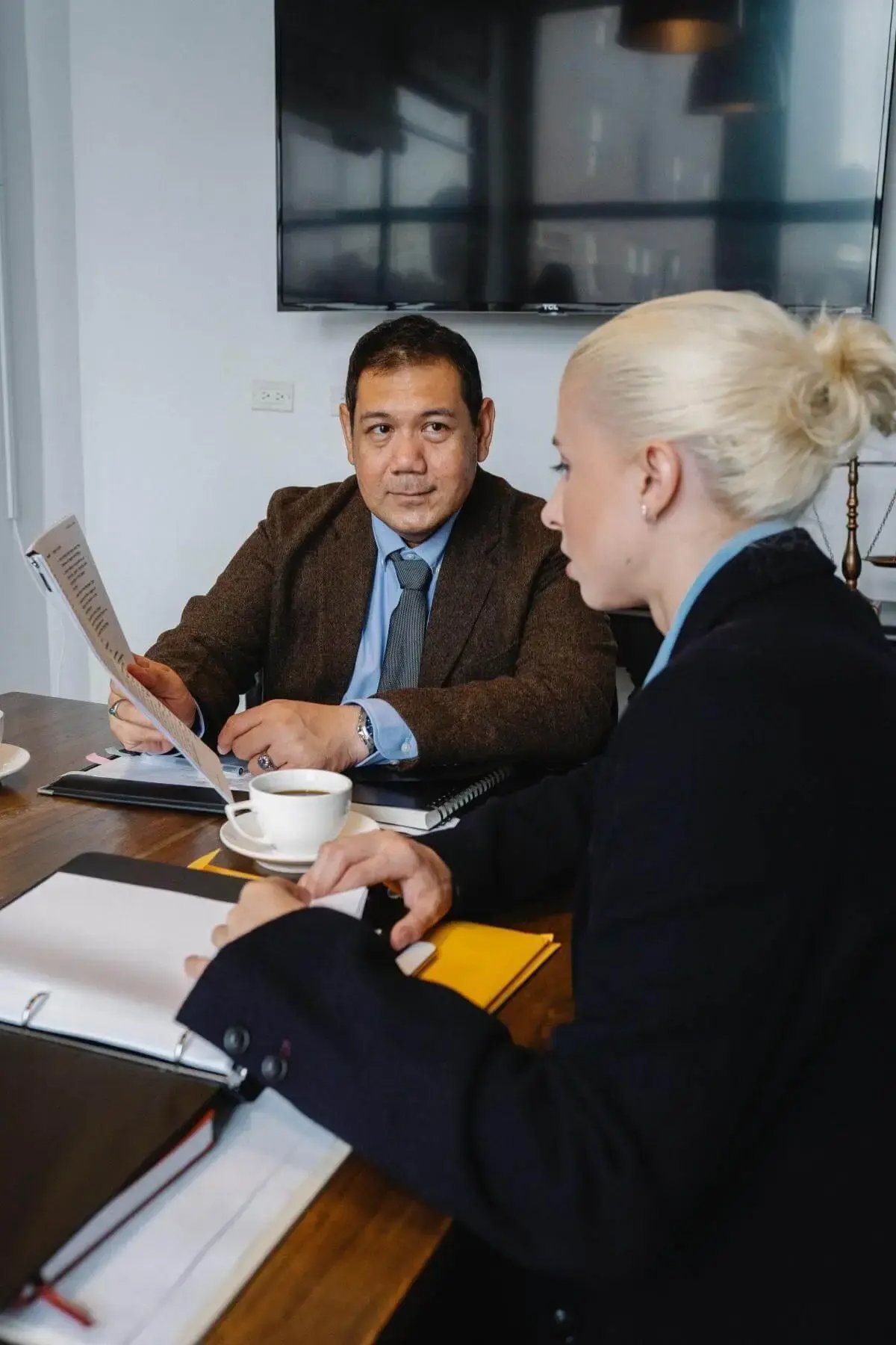 A businessman and businesswoman are sitting at a desk looking at important business documents together