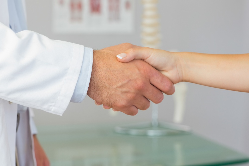 Close up of patient shaking hands with doctor in bright office