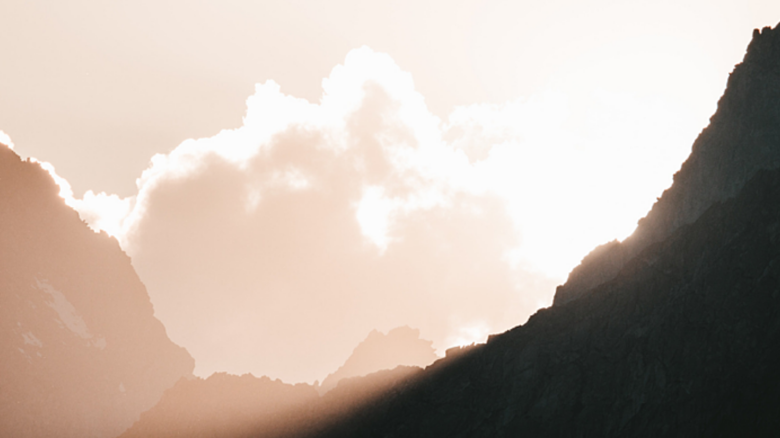 Image of mountains with sunlight coming over the top.